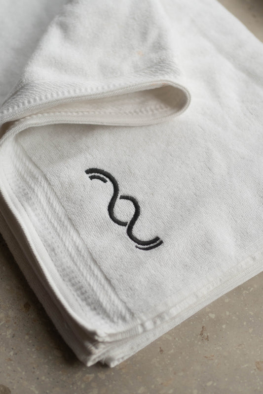 White towel with black embroidered design on a neutral background